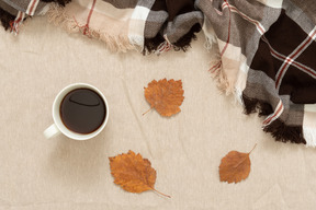 Una taza de café negro y un plaid.