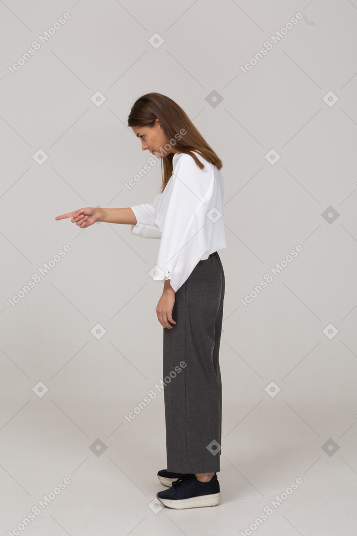 Vista laterale di una giovane donna in abiti da ufficio che punta il dito
