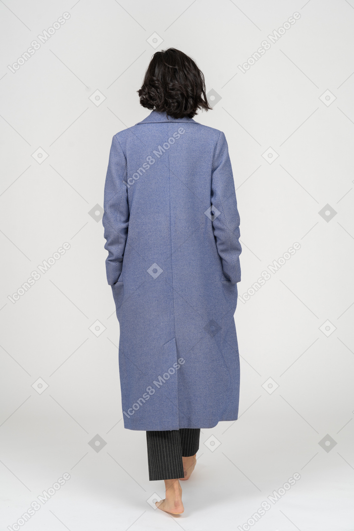Vue arrière de la femme en manteau marchant pieds nus