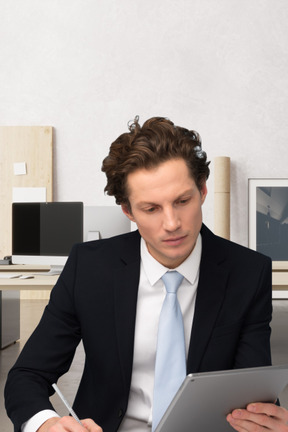 Junger mann hält tablet in der hand und macht sich notizen