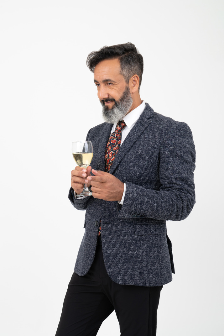 Man in suit slightly smiling and holding a glass
