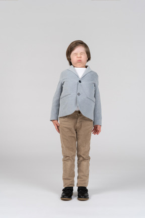 Young boy in jacket and pants about to sneeze