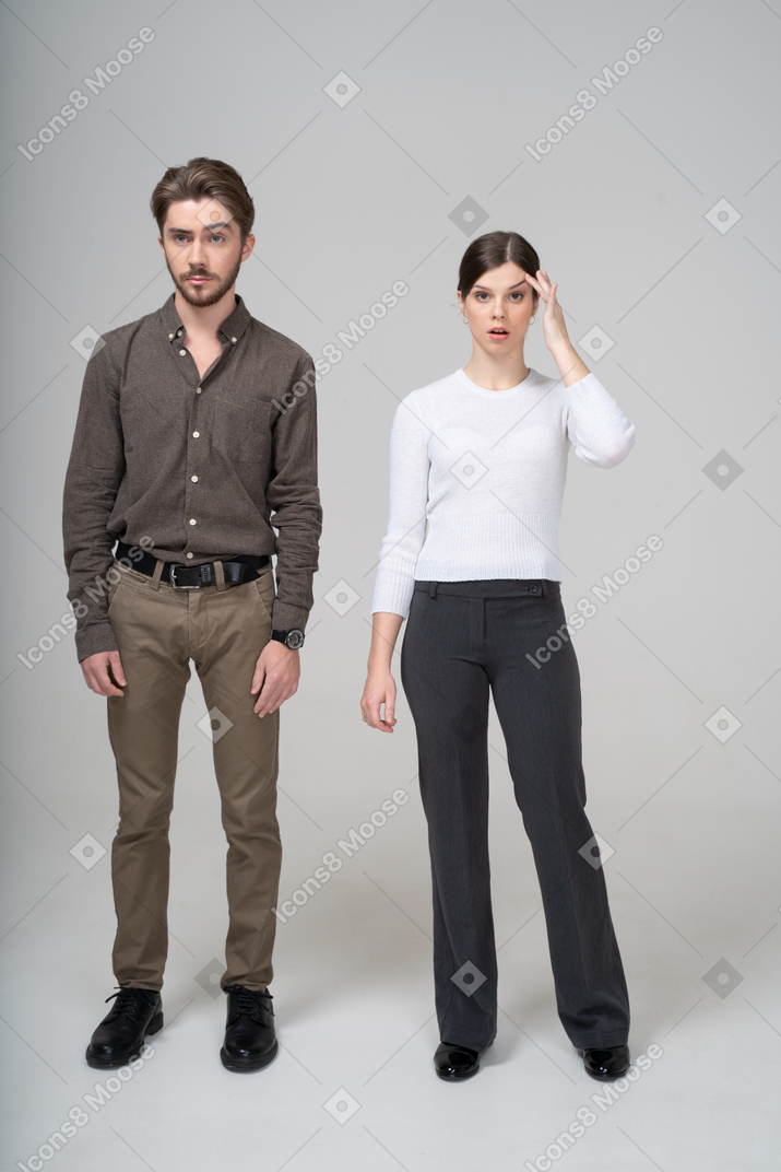 オフィス服を着た若い男性と頭に触れる若い女性のフルレングス