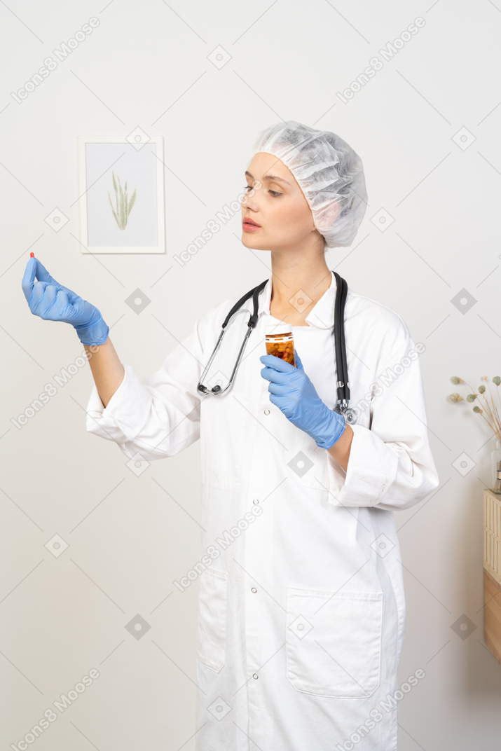 Three-quarter view of a young female doctor offering a pill
