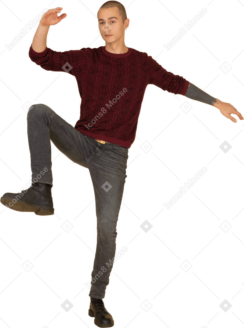 Вид спереди балансирующего молодого человека в красном пуловере, поднимающего руки