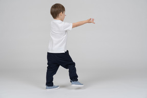 Rear view of boy running with his arms outstretched forward