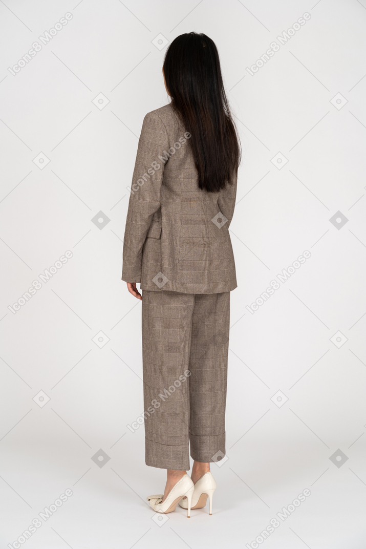 一位年轻的女士，穿着棕色西装往下看的四分之三后视图
