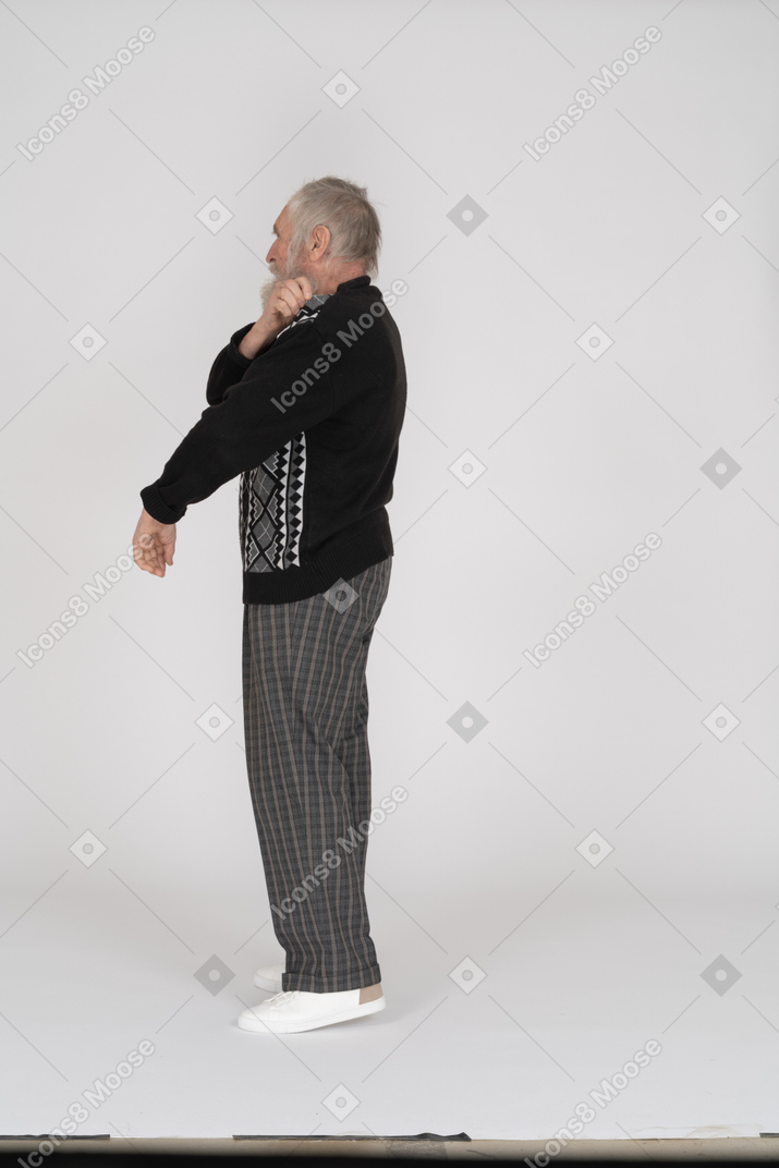 Вид сбоку на пожилого мужчину, натягивающего свитер