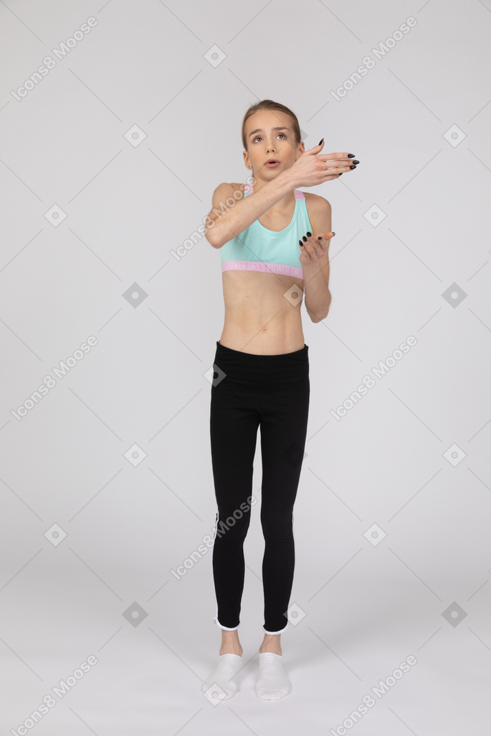 Front view of a teen girl in sportswear raising hands and arguing