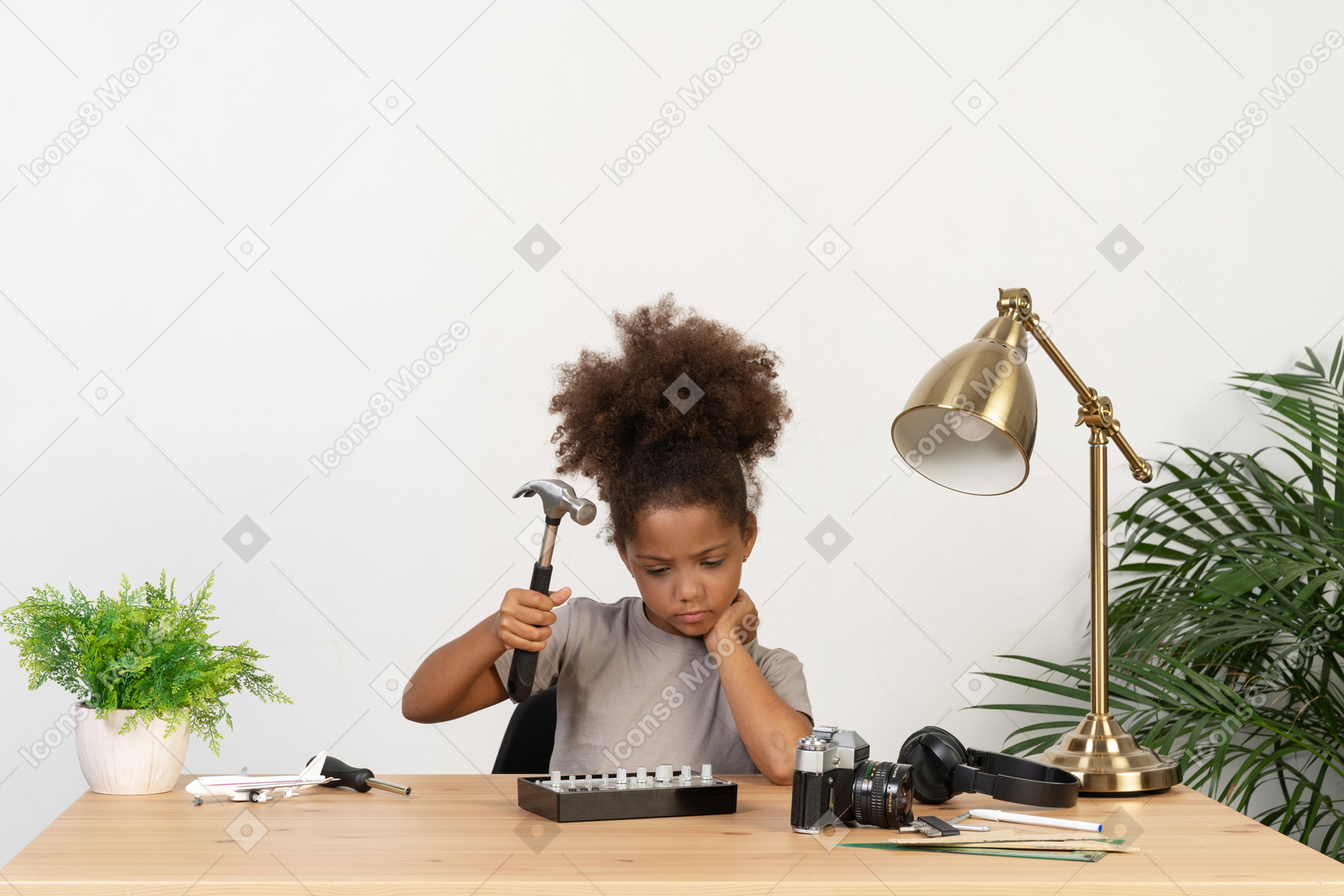 Curly african girl playing with a hammer at the table