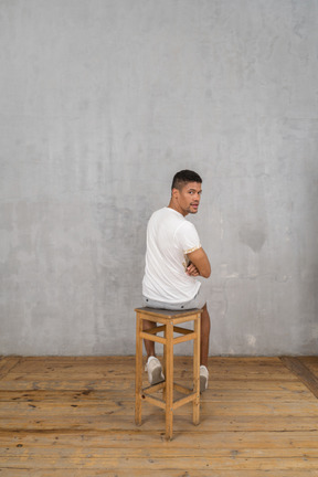 Rear view of man sitting and looking at camera