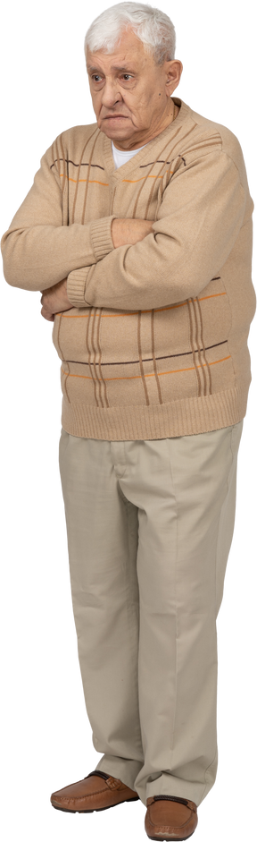 Вид спереди грустного старика в повседневной одежде, стоящего со скрещенными руками
