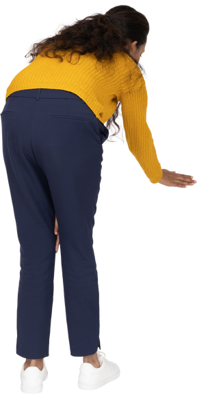 Rear view of a girl in casual clothes bending down