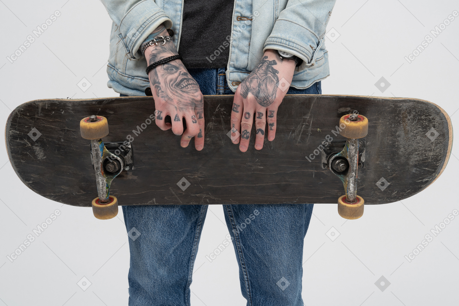 Holding a skateboard with both tattooed hands