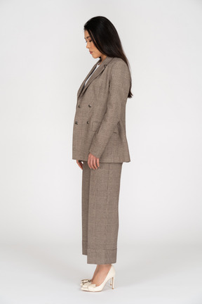 Side view of a young lady in brown business suit looking down