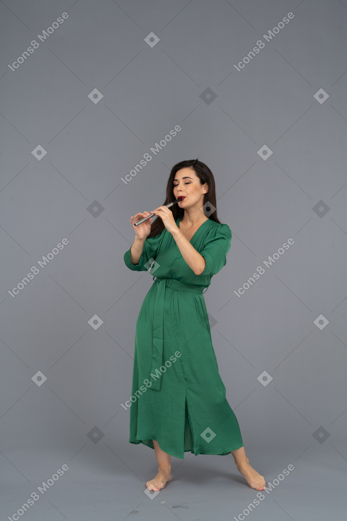 Front view of a young lady in green dress playing the flute