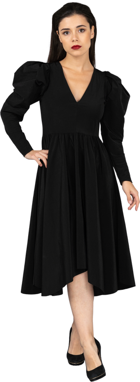 Front view of a young lady in a black dress putting hand on hip