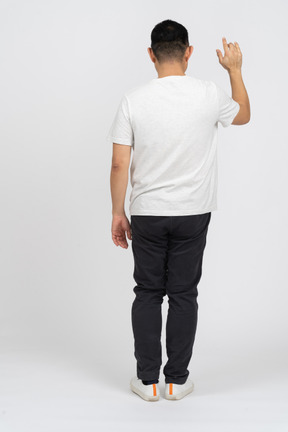 Back view of a man in casual clothes standing with raised hand