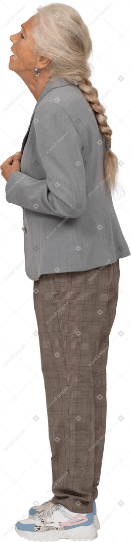 Вид сбоку расстроенной старушки в сером пиджаке, стоящей в профиль