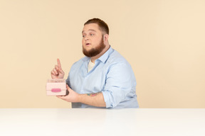 Grande homem sentado à mesa e segurando a lancheira