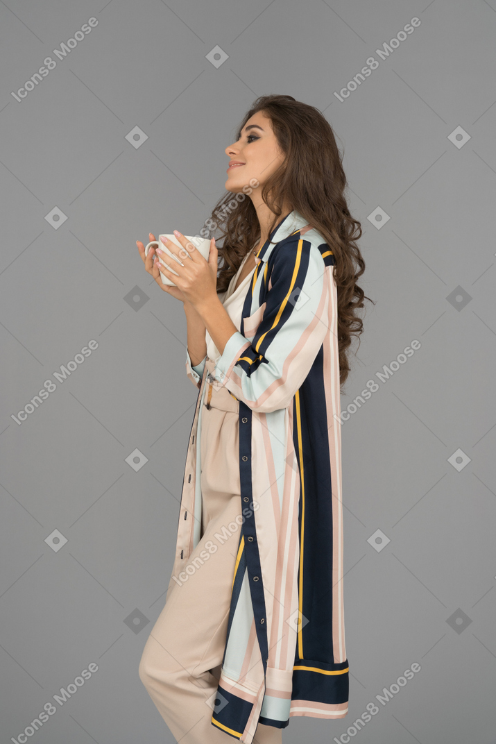 Cheerful young arab woman holding white cup with both hands