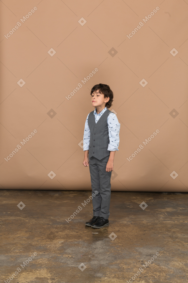 Vista laterale di un ragazzo in abito grigio che fa smorfie