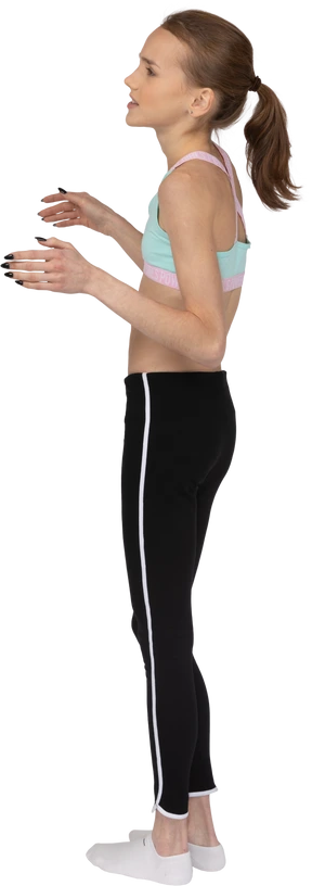 Three-quarter back view of a perplexed teen girl in sportswear raising hands