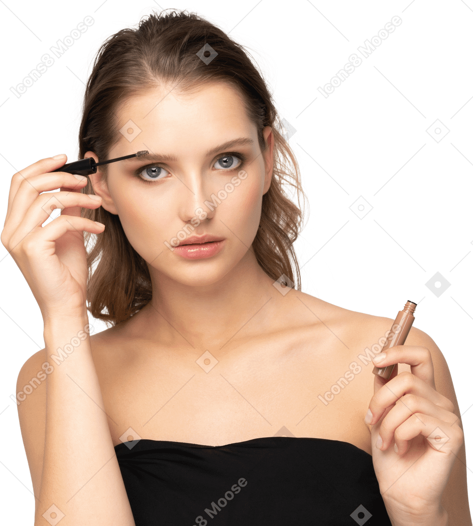 Vue de face d'une jeune femme portant un haut noir tenant se brosser les sourcils