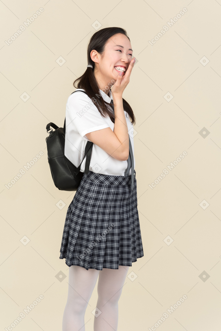 Laughing asian school girl touching face