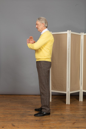 Vista lateral de un anciano involuntario cruzando las manos