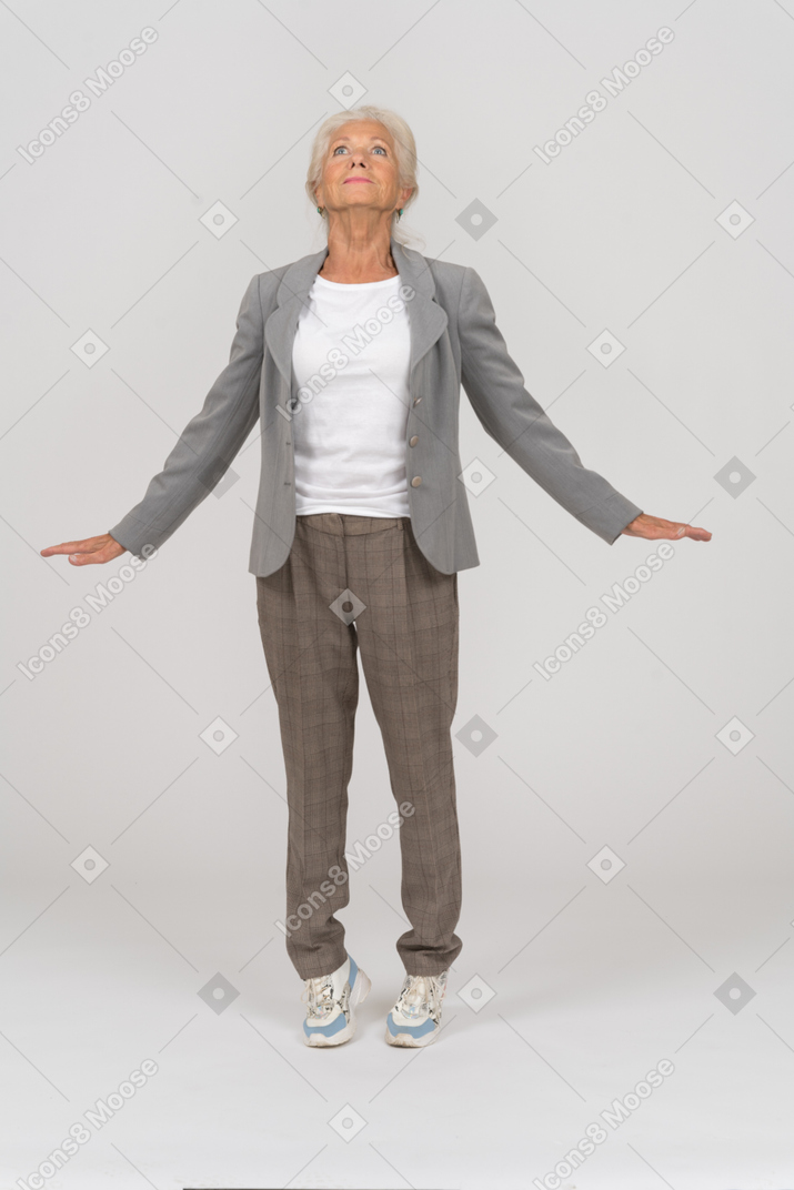 Vue de face d'une vieille dame en costume debout sur les orteils et écartant les bras