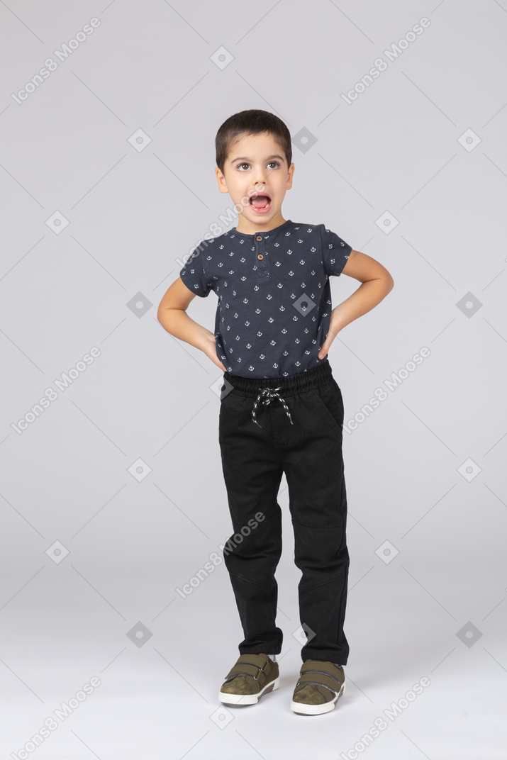 Vista frontal de un chico lindo emocional posando con las manos en las caderas