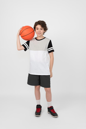 Boy holding basketball ball on his shoulder
