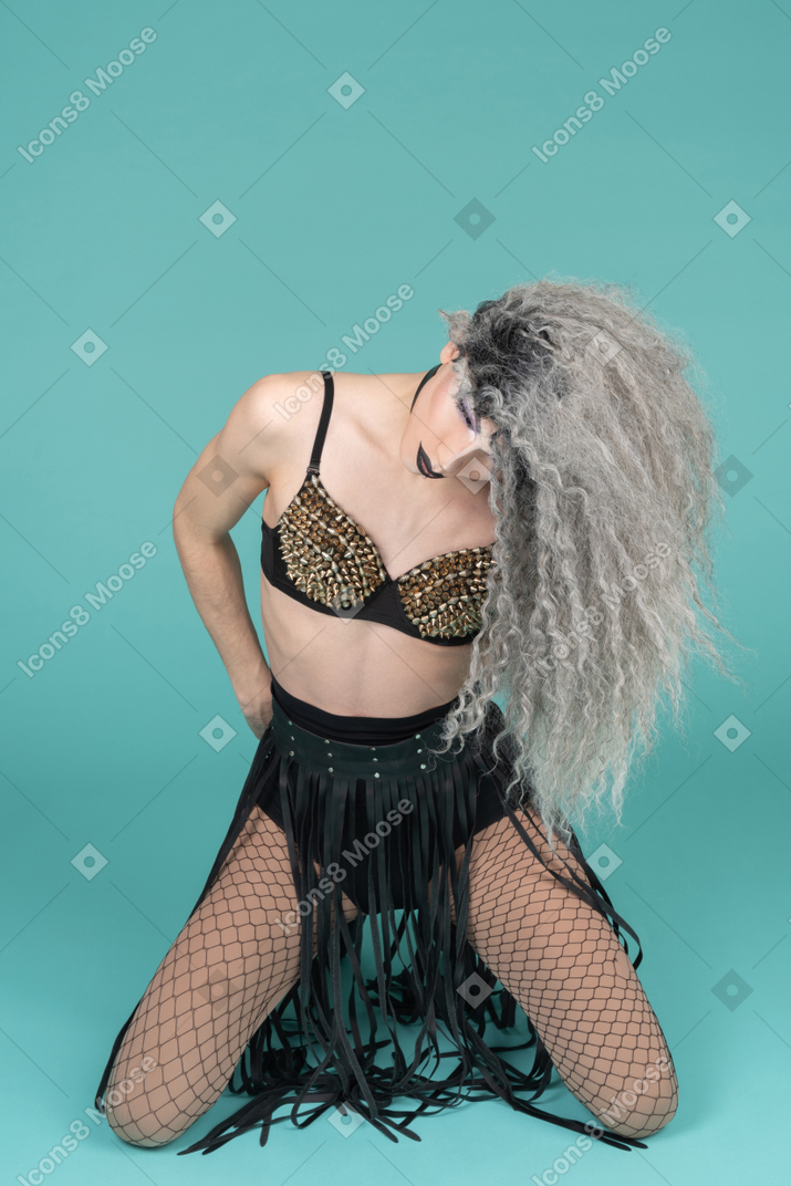 Drag queen standing on knees with their head down