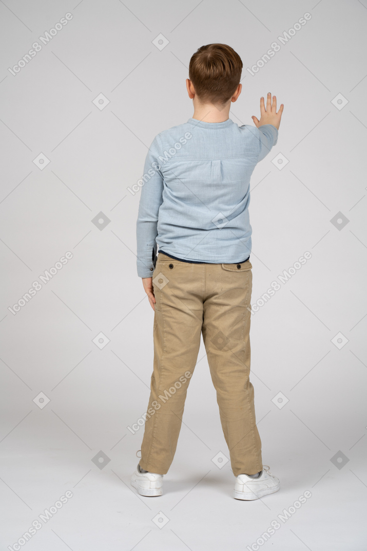 Vista traseira de um menino de pé com o braço estendido
