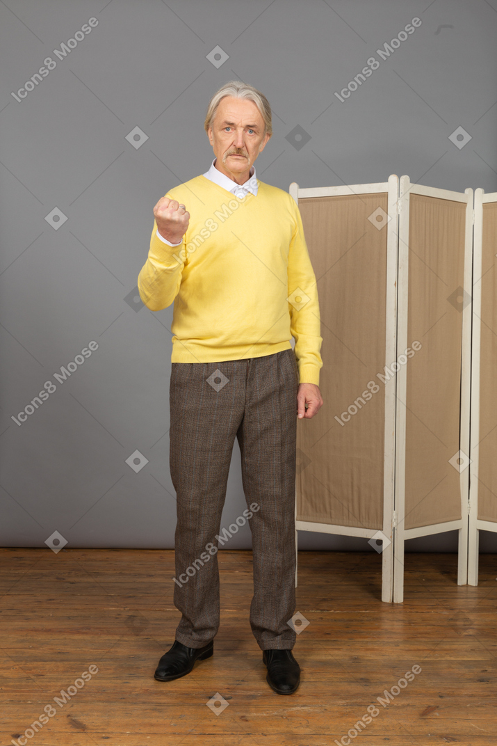 Front view of an angry old man clenching fist