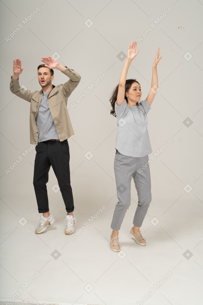 Giovane uomo e donna con le mani in alto