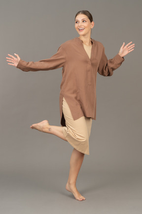 Front view of a woman standing barefoot on tiptoe with lifted leg