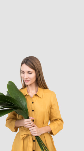 A woman in a yellow dress holding a green plant