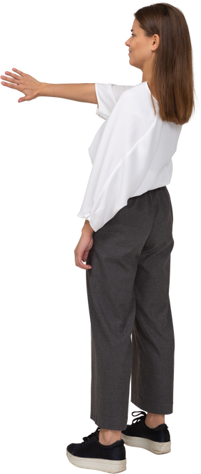 Vista posteriore di tre quarti di una giovane donna dispiaciuta in abiti da ufficio che allunga il braccio