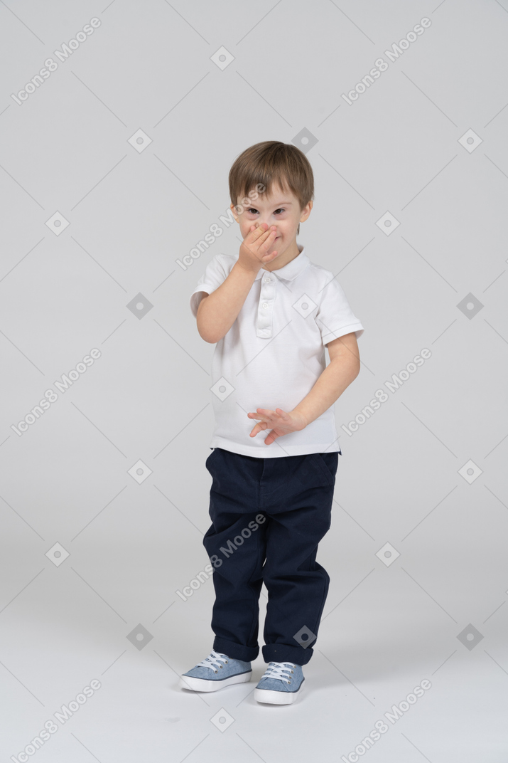 Front view of a little boy covering his nose
