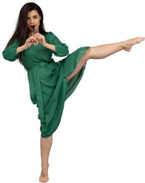 Front view of a dancing young lady in green dress playing flute