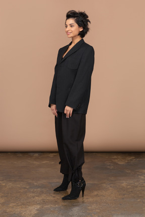 Vue de trois quarts d'une femme d'affaires portant un costume noir et souriant