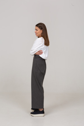 Vista posteriore di tre quarti di una giovane donna riluttante in abiti da ufficio che incrociano le braccia