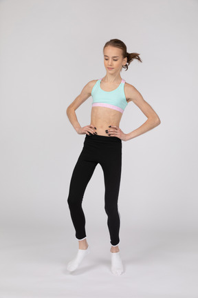 Front view of a teen girl in sportswear putting hands on hips and bending knees