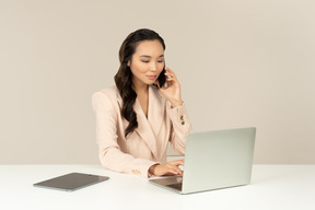 Employé de bureau femme asiatique impliqué dans une conversation téléphonique