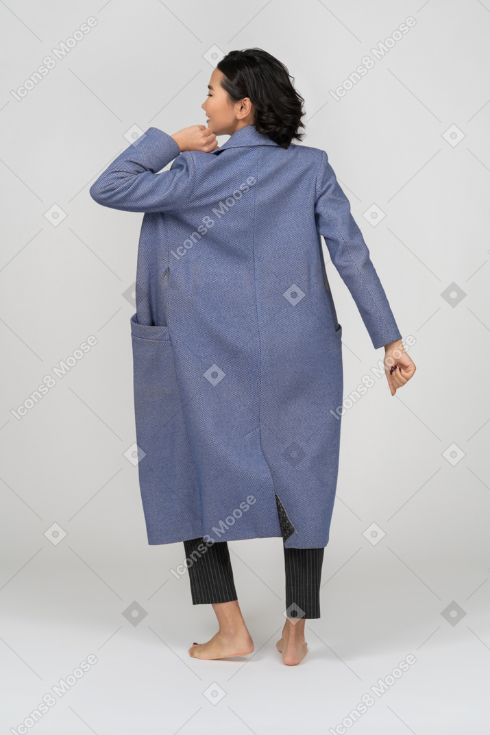 팔을 구부린 코트를 입은 여성의 뒷모습