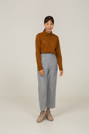 Vista frontal de una mujer asiática joven sonriente en calzones y blusa