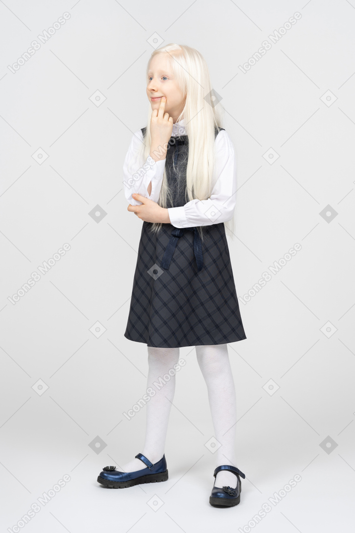 Schoolgirl putting finger to mouth, looking distracted