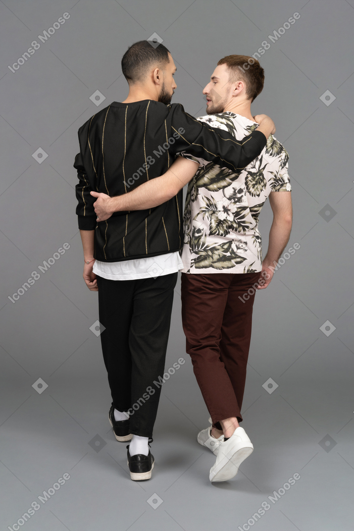 Back view of two young men walking and half-hugging each other